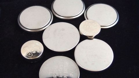 Eine Ansammlung von verschiedenen Batterien liegt auf einer dunklen Oberfläche, bereit für den Batteriewechsel bei Hörgeräten.