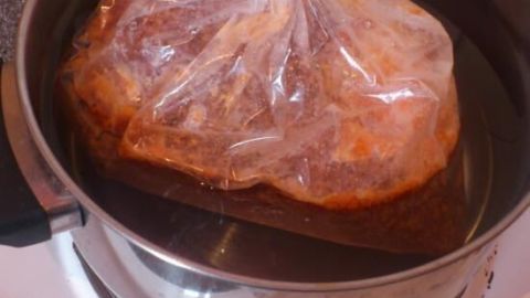 Eine Plastiktüte mit gefrorener Soße wird in einem Topf mit heißem Wasser zum Auftauen verwendet.