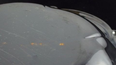 Ein Edelstahlkochtopf mit sichtbarem Rost und Beschädigungen liegt in einem dunklen Umfeld, was die Abnutzung betont.