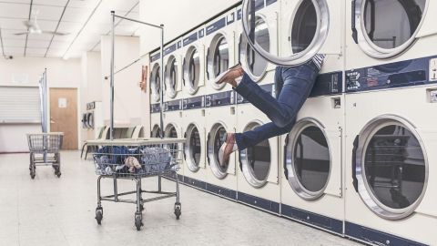Ein Mensch greift in eine Waschmaschine, um Sockenpaare nach dem Waschen zu finden, in einem hellen Waschsalon.