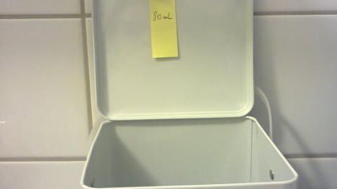Eine geöffnete Waschmitteldose steht auf einer Kacheloberfläche, bereit zum genauen Dosieren des Waschmittels.