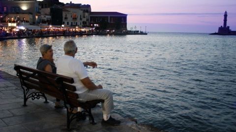 Zwei ältere Personen sitzen auf einer Bank am Wasser, während sie den Sonnenuntergang genießen und Erinnerungen teilen.