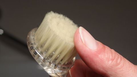 Eine Hand hält ein sanftes Gesichtsbürstchen, bereit zur Anwendung für das Gesicht reinigen und sanftes Peeling.
