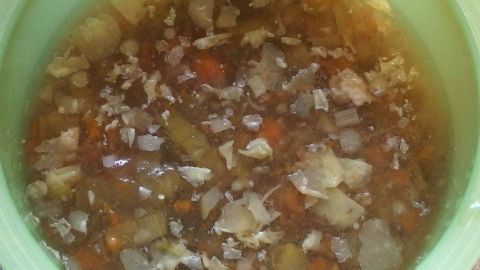 Ein Suppentopf enthält eine bräunliche Suppe mit Stückchen von Gemüse und Fleisch, die sorgfältig zubereitet wurde.
