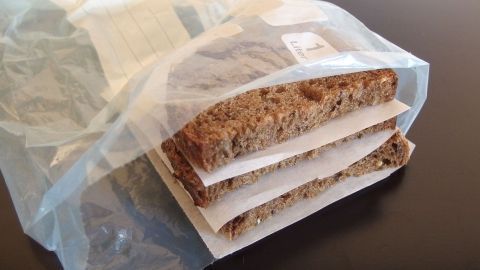 Auf einem Tisch liegt eine Tüte mit leicht portionierbarem Brot, das in Scheiben eingefroren und durch Papier getrennt ist.