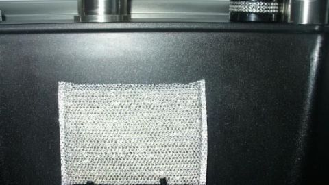 Ein graues Aufbewahrungstuch hängt an einem Küchenschrank, während ein Spülschwamm darin verstaut ist, um ihn unsichtbar zu lagern.