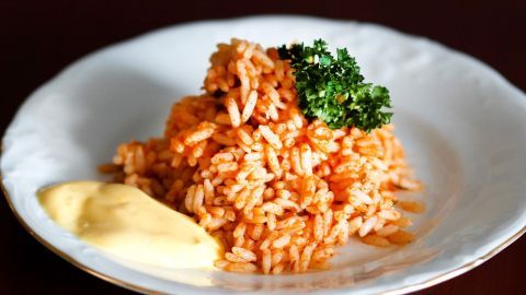 Ein geschmackvoller Berg gelber Reis wird von einer cremigen weißen Sauce und frischer Petersilie begleitet.