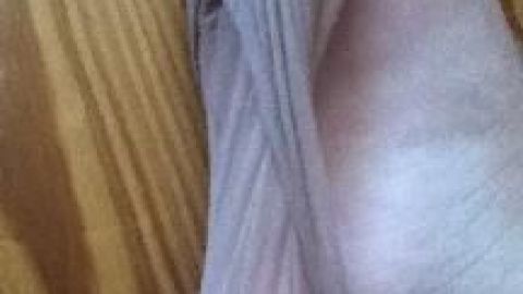 Ein Fuß spannt eine durchsichtige Strumpfhose auf einem Holzfußboden.