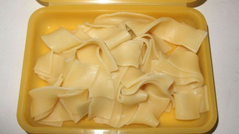 In einem gelben Behälter liegen frisch gekochte, aromatische Nudeln, die sanft übereinander geschichtet sind.