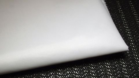 Strahlend weiße Wäsche liegt auf einer texturierten schwarzen Oberfläche, bereit zum Einsatz oder zur Präsentation.