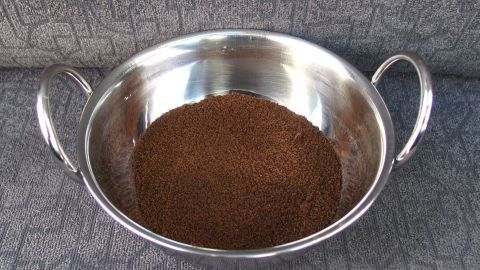 Ein silberner Behälter mit gemahlenem Kaffee steht auf einem Autositz, um den Geruch im Auto zu neutralisieren.