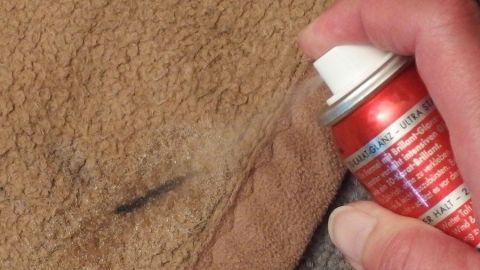 Eine Spraydose wird auf einen Kleidungsfleck gesprüht, um Marker-Flecken effizient zu entfernen.