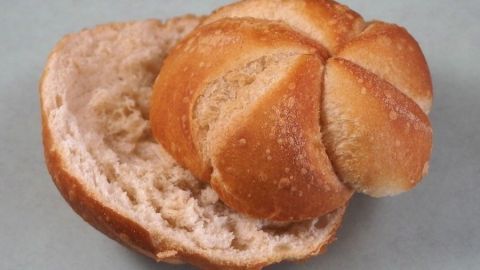 Eine Semmel liegt offen auf einer Fläche, die weiche Innenseite zeigt, bereit zur Verwendung oder zum Verzehr.