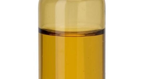 Eine braune Glasflasche mit Teebaumöl steht vor weißem Hintergrund.