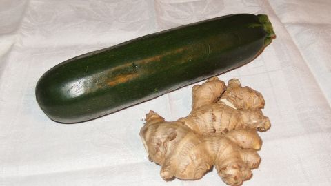 Grüne Zucchini und frischer Ingwer liegen auf einem weißen Tuch, bereit für die Zubereitung von Ingwer-Zucchini Marmelade.