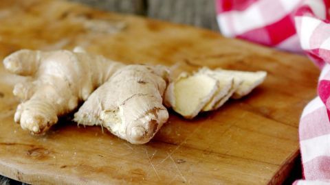 Frischer Ingwer liegt auf einem Holzbrett, umgeben von einem karierten Tuch, ideal zur Förderung des Kreislaufs bei Hitze.