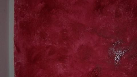 Rote Wand zeigt Wischtechnik-Textur, verleiht künstlerischen Touch im Raum. Links oben ein kleines Rohrfragment.