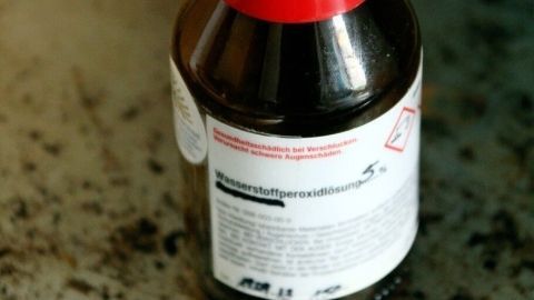 Eine braune Flasche mit rotem Deckel steht auf einer schmutzigen Oberfläche, bereit zur Reinigung von Plastikflaschen.