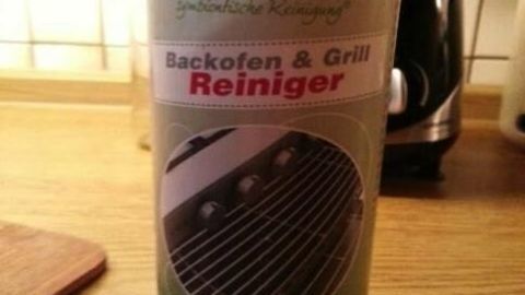 Reinigerflasche steht auf der Küchenarbeitsplatte, zeigt Bild eines Grillrosts. Text: "prowin symbiontische Reinigung, Backofen & Grill Reiniger, Stärkste Fettlösekraft".