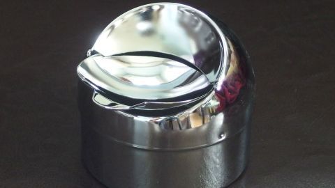 Vor dem ersten Gebrauch oder nach der Reinigung eines Aschenbechers, diesen mit Autopolitur einreiben. So bleibt er sauber und nimmt den Geruch von Rauch nicht so stark an. Ein glänzender Aschenbecher aus Metall steht auf einer dunklen Oberfläche, bereit zum Einsatz für saubere Rauchergewohnheiten.