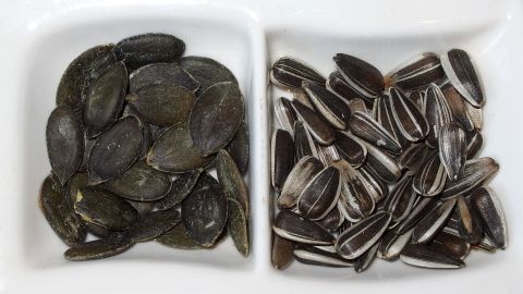 Kürbiskerne und Sonnenblumenkerne liegen in zwei Schalen und zeigen eine klare Unterscheidung zwischen den Sorten.