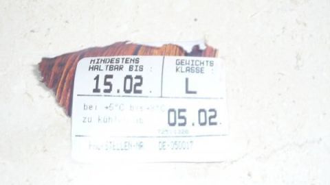 Ein Etikett liegt auf einer Oberfläche und zeigt Haltbarkeitsdaten für Kühlschrankeier an: 15.02 und 05.02.