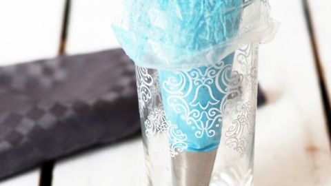 Ein Spritzbeutel steht auf einem Tisch in einem Glas, bereit zum leichteren Befüllen mit Teig oder Creme, umgeben von einer servierbaren Unterlage.