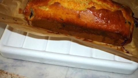 Kuchen liegt auf Papier und einem Tablett, frisch gebacken mit goldener Kruste. Es kühlt auf einer Arbeitsplatte ab.
