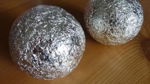 Zwei mit Alufolie umwickelte Kugeln liegen auf einem Tisch. Sie könnten dazu dienen, elektrostatische Aufladung zu reduzieren.