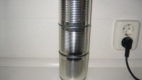 Drei leere Dosen stapeln sich zu einem Turm auf einer weißen Küchenarbeitsfläche neben einer Steckdose.