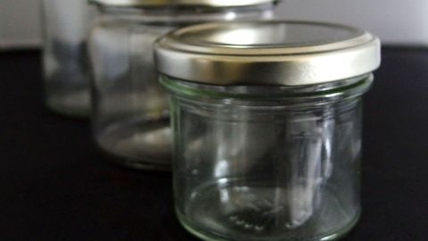 Eingemachte Gläser stehen ordentlich auf einer dunklen Oberfläche, bereit zum Befüllen und Konservieren von Lebensmitteln.