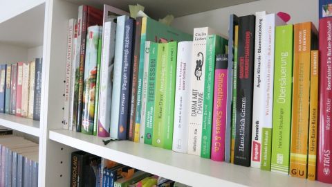 Buch geschenkt bekommen, dass du nicht brauchst? Möglicherweise freut sich die örtliche Bücherei über eine Spende. Einfach mal nachfragen. Ein Buchregal mit vielen bunten Büchern, einige sind falsch platziert, was auf das geschenkte Buch hinweist.