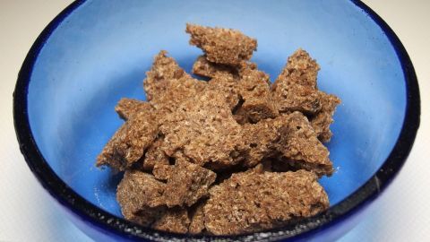 Vollkornbrot-Brösel liegen in einer blauen Schüssel und wirken appetitlich und gesund. Sie sind grob zerbröselt.