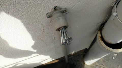 Ein abgebrochener Wasserhahn liegt an einer Wand, während er herausgedreht wird; im Hintergrund sind Rohre sichtbar.