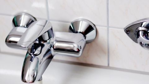 Wasserhahn glänzt sauber an gefliester Wand, bereit für schnelle Entkalkung; links im Bild ist "GROHE" eingeprägt.