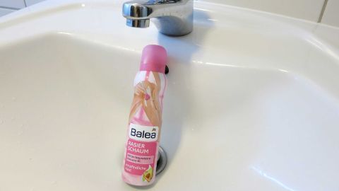 Waschbecken mit Rasierschaum reinigen: Einfach aufsprühen, verreiben, abwaschen und trocken reiben. Ein Rasierschaum liegt auf einem Waschbecken, während ein Wasserhahn im Hintergrund für Hygiene sorgt.