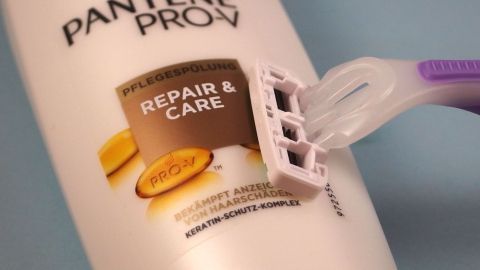 Vor dem Rasieren der Haare, diese mit Haarspülung behandeln: Verhindert Bildung von Pickelchen. Ein Rasierer steht auf einer Haarspülung von Pantene Pro-V. Die Spülung mit dem Label "Repair & Care" ist gut sichtbar.