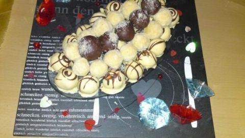 Köstliche Eierlikör-Pralinen liegen auf einem dekorierten Teller, umgeben von farbigen Herzchen und Glitzersteinen.