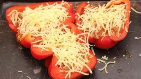 Gefüllte Paprika liegen in einer Auflaufform und sind mit Käse überbacken, bereit zum Backen in der Küche.