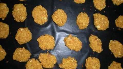 Reisplätzchen liegen auf einem Backblech, bereit zum Backen. Die goldene Panierung verleiht ihnen eine knusprige Textur.