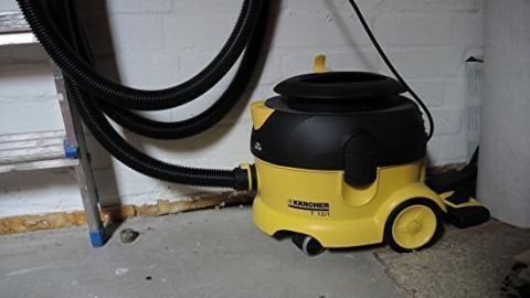Ein Staubsauger steht in einem Raum mit grauem Boden und weißen Wänden, bereit zum Einsatz für praktisches Staubsaugen.