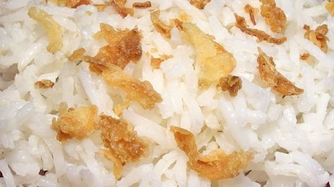 Auf einem Teller liegt locker gegarter Reis mit goldbraunen, knusprigen Zwiebelstückchen, perfektes Gericht ohne Kochbeutel.