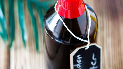 Schwedenbitterflasche steht auf einem Holztisch, während sie für die Linderung von Mückenstichen genutzt wird.