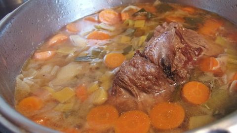 Ein Dampfdrucktopf kocht köstliche Brühe mit Gemüse und Fleisch auf dem Herd, um ein schnelles Gericht zuzubereiten.