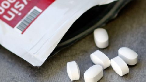 Weiße Lysin-Tabletten liegen auf einem Tisch, während die Packung geöffnet ist, was auf eine Anwendung zur Herpesbekämpfung hinweist.