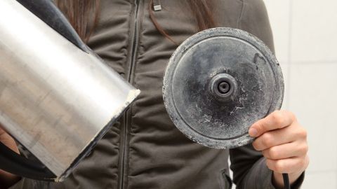 Ein Wasserkocher mit Ablagerungen wird von einer Person gehalten, um effektiv mit Zitronensäure entkalkt zu werden.