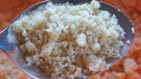 Ein Löffel voller Butterstreusel wird gehalten, umgeben von einer unscharfen, hellen Küchenszene.
