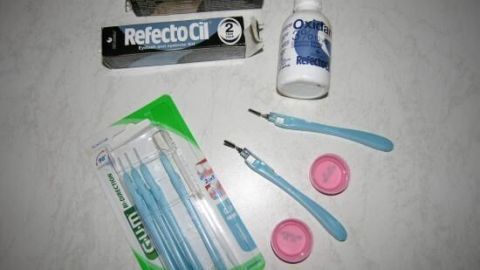 Zwei Wimpernfärbemittel und Zubehör, bereit zum Färben, liegen auf einem hellen Tisch.