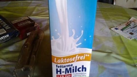 Ein Milchkarton steht auf einem Tisch und zeigt schäumende, laktosefreie H-Milch, die zwischendurch serviert wird.