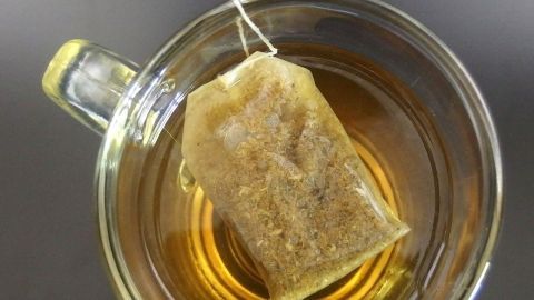 Ein Teebeutel hängt über der Tasse mit heißem Tee, der zur Linderung von Halsschmerzen dient.